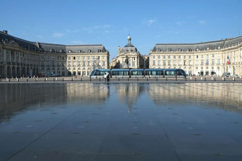 La place de la Bourse à Bordeaux reflétée dans le miroir d'eau, avec un tramway